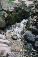 Flowing cold transparent water on wet rocks