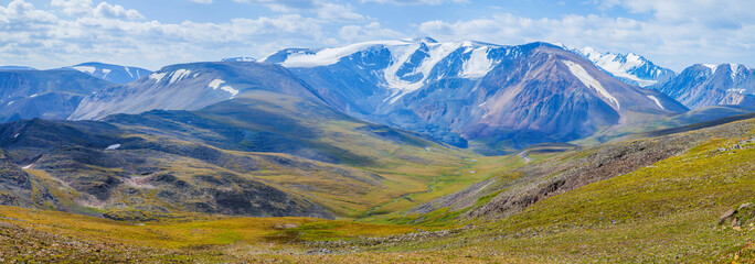Fototapeta na wymiar Panoramic view of a mountain valley. Tundra, treeless mountain slopes, snow-capped peaks. 