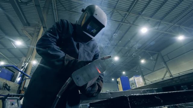 Welding operator is working with iron in a workshop. Professional Welder Working at factory facility.