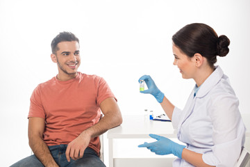 Smiling doctor showing vaccine to patient isolated on white