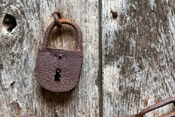 old rusty closed lock on an ancient wooden door