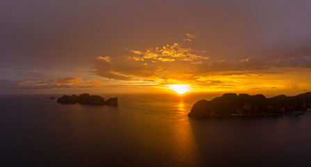 Naklejka na ściany i meble Aerial view of Phi Phi, Maya beach with blue turquoise seawater, mountain hills, and tropical green forest trees at sunset with Andaman sea island in summer, Thailand in travel trip. Nature. Panorama