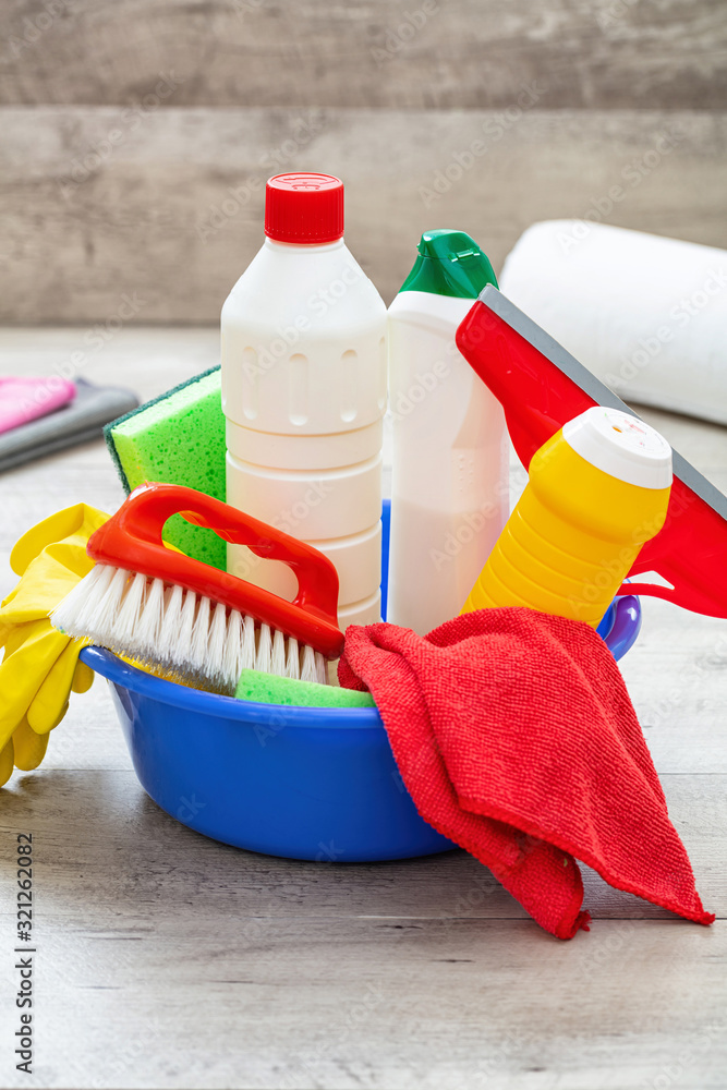 Wall mural cleaning supplies in a blue bowl, wooden floor background.