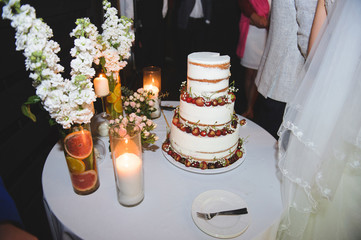 wedding cake with berries on table with candles and flowers