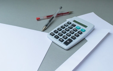 Empty letter and envelope with a calculator and pens and euro coins on a modern blue background