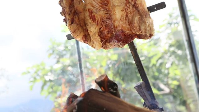 Montage of argentinian asado cooked on a spit on embers and slicing it up. Barbecued meat.