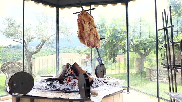 Wide angle shot of argentinian asado beef or lamb ribs sizzling on embers. Barbecued meat.