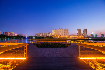 The wooden walkway by the river and the night view of the city