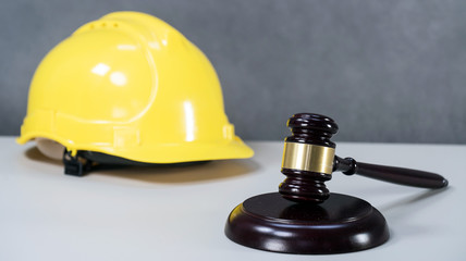 Closeup of wooden mallet and yellow hardhat on table in courtroom