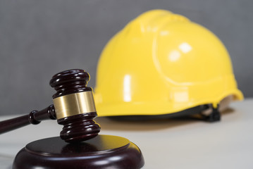 Closeup of wooden mallet and yellow hardhat on table in courtroom