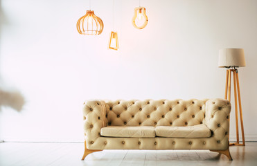 Cozy sofa. Close up photo of beige couch and lamp standing against a white wall in a modern flat.