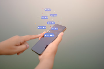 Person using a social media marketing concept on mobile phone with notification icons of like, message, comment and star above smartphone screen.