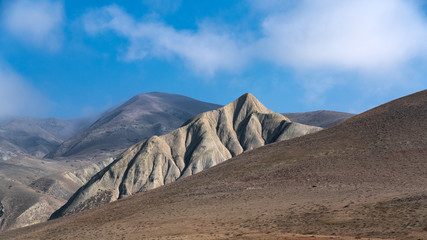 Fototapeta na wymiar Mountain peaks with clouds on a blue sky
