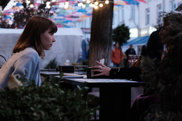 Two pretty girl friends talk and drink tea in cafe, outdoors