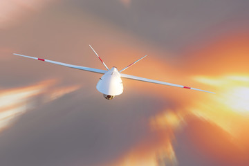 Unmanned military drone patrols high in the sky at sunset. The view is straight ahead.