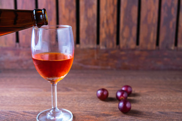 .Pour red wine into a glass of wine on a wooden background.