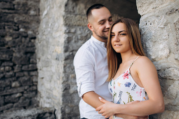 Wonderful couple in love staying near the stone wall of old castle