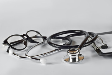 Stethoscope with glasses and folder on a white background. Medical equipment on the table.