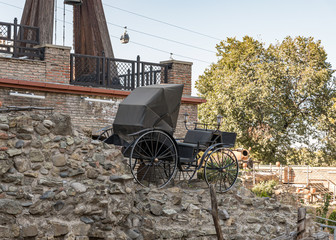 Fototapeta premium A copy of an old carriage stands near the Forty Martyrs of Sebastian Monastery building on the Samghebro St. in Tbilisi city in Georgia