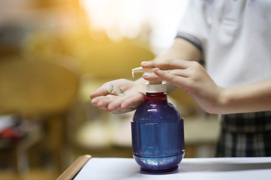 Hand of schoolgirl that applying alcohol gel as hand sanitizer at a school.