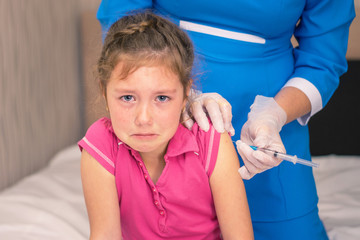 Portrait of a crying baby who is being injected. The child is hurt by vaccines. Children's medical concept A little girl in tears is very afraid of vaccination.