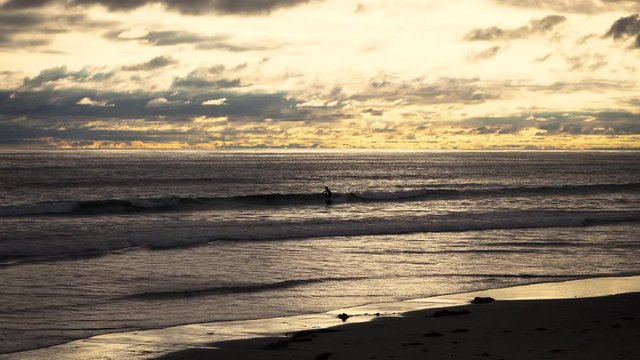 Surfers on waves at golden hour, beautiful sunset on the beach