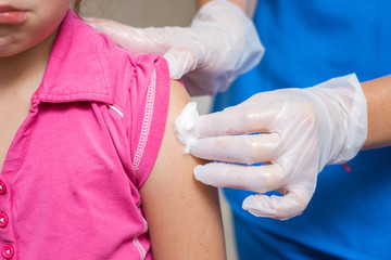 Medical concept. Vaccination is a close-up. A doctor in gloves presses cotton to the patient’s shoulder. Disinfection after an antiviral injection.