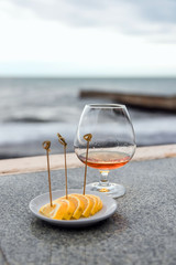 a glass of cognac or brandy, against the sea.