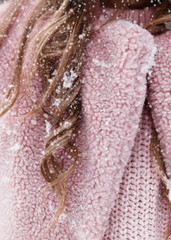 A beautiful pretty young girl with curly hair and a snow-white smile in a pink fur coat is walking and fooling around in the winter forest against the background of snow and trees, enjoy