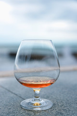 a glass of cognac or brandy, against the sea.