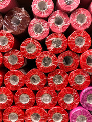 rolls of packaging for red flowers are on the shelf for sale in the warehouse