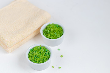 The concept of spa treatment, with natural, fragrant two-tone, sea bath salt and bath towels. On a white background