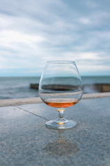 a glass of cognac or brandy, against the sea.