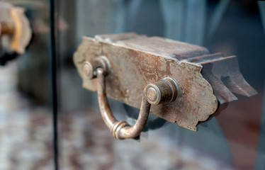 Penang, Malaysia - January 21, 2020 : Vintage Bronze door handle on main entrance frameless glass door in one of the shop house historic colonial district of Georgetown.