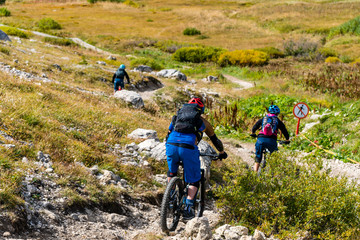 Fototapeta na wymiar Mountainbiker auf einem steinigen Singletrail abwärts mit Verbotsschild für Wanderer