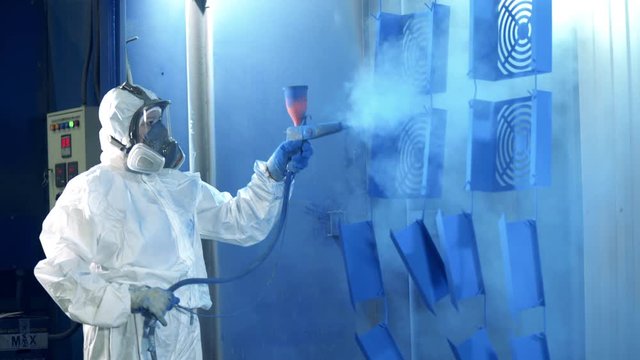 Female worker is air-brushing metal pieces