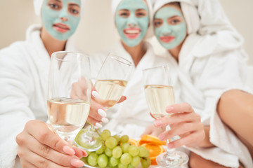 Female friends drinking wine in bed.