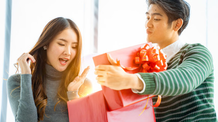 Concept of Surprise and wonderful gift in valentine's day.Attractive young asian adult couple is opening red box. Happy young wife with husband looking at valentine gift.Couple in love.