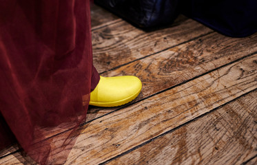 Braut in einem weinroten Kleid zeigt ihre gelben Gummistiefel auf der Hochzeitsfeier