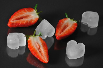 Fresh strawberries and ice on black with reflection