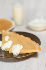 Maslenitsa is a holiday at the end of February . pancakes with sour cream and milk on a light wooden background. close up. blini. space for text. vertical photo