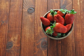 Sweet fresh strawberries in a bowl on wooden table