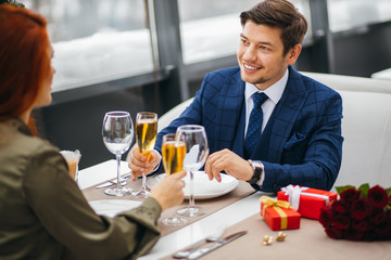 caucasian couple celebrate their anniversary or birthday in rich representative restaurant. charming redhaired lady and handsome guy in tuxedo happy together. love, relationships, emotions concept