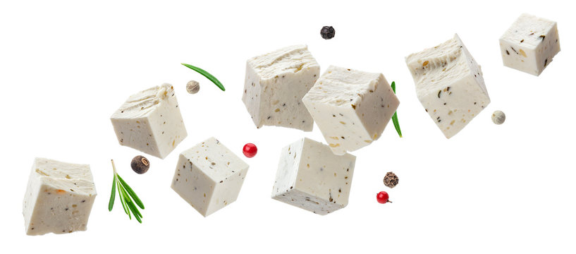 Falling feta cubes with herbs isolated on white background
