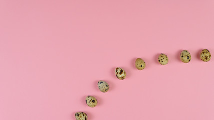 Quail eggs roll out from a burlap bag on wooden background, flat lay.