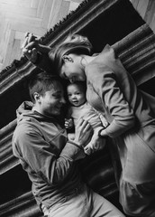 Naklejka na ściany i meble Portrait of a young happy family with the kid. Beautiful family hugs. Black and white