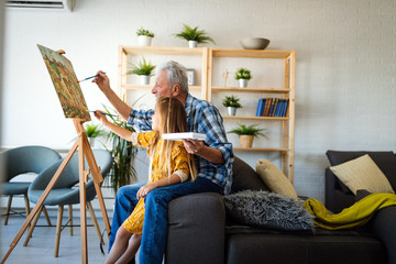 Portrait of senior man, grandfather teaching children painting. Happy family time