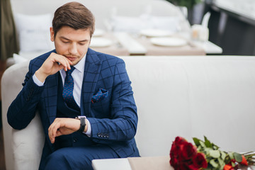 young handsome guy sit waiting for a girlfriend, romantic gallant guy in stylish tuxedo before...