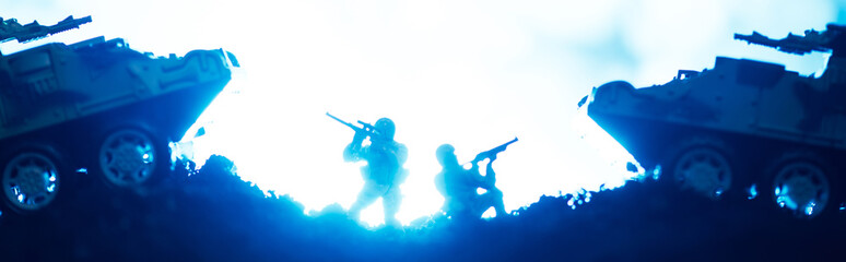 Battle scene with toy warriors and tanks with lighting on blue background, panoramic shot