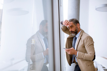 Fototapeta premium Senior businessman using mobile phone in modern office